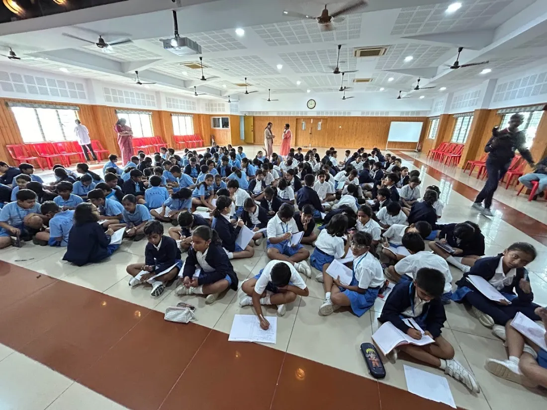 Students seated on a school hall floor during a writing workshop